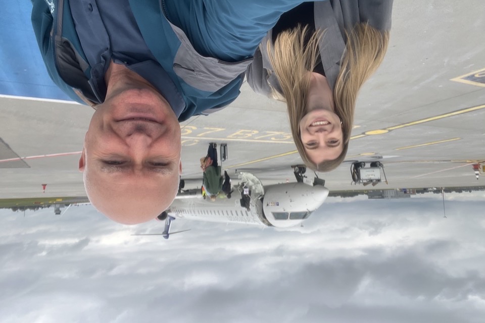 Två kollegor tar en selfie utomhus vid flygplatsen